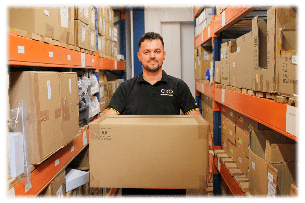 Image of Damian from CKO, holding a box in the warehouse.